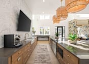 Thumbnail 15 of 61 - A modern kitchen with a black television mounted on the wall at Verity Luxury Apartments, Vero Beach, Florida