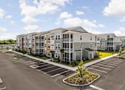 Thumbnail 37 of 61 - A large building with a parking lot in front of it at Verity Luxury Apartments, Vero Beach
