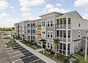 Thumbnail 34 of 61 - A row of modern townhouses with a parking lot in front at Verity Luxury Apartments, Vero Beach, FL