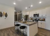 Thumbnail 6 of 38 - a kitchen with white cabinets and a large island with two stools  at Upland Flats, Colorado Springs, CO