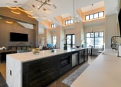 Thumbnail 24 of 38 - a kitchen with a large center island with a breakfast bar and a living room in the background  at Upland Flats, Colorado Springs, Colorado