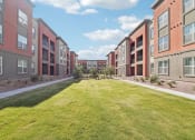 Thumbnail 8 of 108 - a grassy area in front of an apartment building at The Maddox Luxury Apartment Homes, Buckeye  