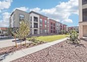 Thumbnail 27 of 108 - an exterior view of a row of apartment buildings with a lawn and sidewalk at The Maddox Luxury Apartment Homes, Buckeye, AZ  