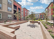 Thumbnail 19 of 108 - an outdoor area with benches and trees in front of an apartment building at The Maddox Luxury Apartment Homes, Buckeye, AZ 85326  