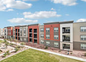 Thumbnail 29 of 108 - an apartment building with a green lawn and a blue sky at The Maddox Luxury Apartment Homes, Buckeye  