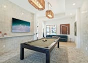 Thumbnail 28 of 108 - a pool table in a living room with a painting on the wall at The Maddox Luxury Apartment Homes, Buckeye, 85326  