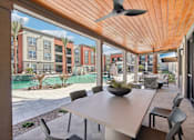 Thumbnail 15 of 108 - a patio with a table and chairs near a pool at The Maddox Luxury Apartment Homes, Buckeye, 85326  