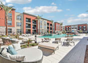 Thumbnail 38 of 108 - a pool with lounge chairs and tables in front of an apartment building at The Maddox Luxury Apartment Homes, Arizona, 85326 