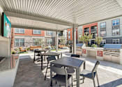 Thumbnail 35 of 108 - a patio with tables and chairs and a grill at The Maddox Luxury Apartment Homes, Buckeye Arizona  
