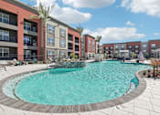 Thumbnail 32 of 108 - a swimming pool with an apartment building in the background at The Maddox Luxury Apartment Homes, Buckeye, AZ 85326  