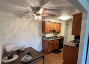Thumbnail 8 of 36 - a kitchen and dining room with a ceiling fan and a table and chairs at Deauville Park Apartments, Monroeville