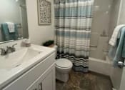 Thumbnail 7 of 16 - A bathroom with a toilet, sink, and shower.