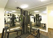 Thumbnail 12 of 16 - A gym with a variety of equipment including a squat rack.