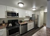 Thumbnail 2 of 16 - A kitchen with white cabinets and stainless steel appliances.