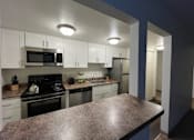 Thumbnail 3 of 16 - A kitchen with white cabinets and a granite counter.