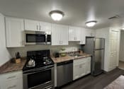 Thumbnail 1 of 16 - A kitchen with white cabinets and stainless steel appliances.