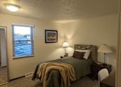 Thumbnail 5 of 18 - A bedroom with a bed, nightstand, and window.