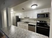 Thumbnail 4 of 16 - A kitchen with granite countertops and white cabinets.