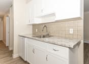 Thumbnail 2 of 40 - A kitchen with white cabinets and a marble countertop.
