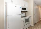 Thumbnail 3 of 40 - A white refrigerator and oven in a kitchen.