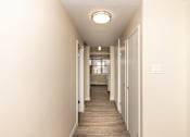 Thumbnail 21 of 40 - A long hallway with doors on both sides and a light on the ceiling.