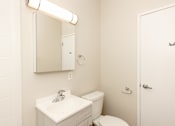 Thumbnail 23 of 40 - A white bathroom with a sink, toilet and mirror.