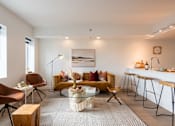 Thumbnail 17 of 36 - A modern living room with a yellow sofa and a glass coffee table.