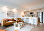 Thumbnail 5 of 36 - A modern living room with a sofa, coffee table, and kitchen area in the background.