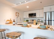 Thumbnail 13 of 36 - A modern kitchen with a white countertop and stainless steel appliances.