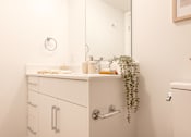 Thumbnail 24 of 36 - A white bathroom with a mirror, sink, and toilet.