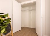 Thumbnail 27 of 36 - A white closet with a wooden floor and a door on the right.