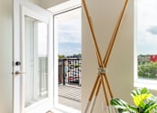 Thumbnail 32 of 36 - A white door with a glass window is open to a balcony with a view of the outside.