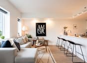 Thumbnail 1 of 47 - A modern living room with a grey sofa, a coffee table, and a bar area with stools.