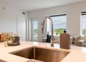 Thumbnail 2 of 47 - A modern kitchen with a copper sink and a view of the outdoors through the window.
