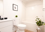 Thumbnail 44 of 47 - A white toilet sits next to a white sink in a small bathroom.