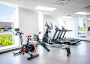 Thumbnail 46 of 47 - A gym with a row of stationary bikes.