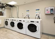 Thumbnail 30 of 31 - A row of white front load washing machines in a laundromat.