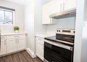 Thumbnail 20 of 33 - a kitchen with white cabinets and a stove and a window