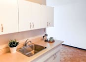Thumbnail 3 of 13 - Spacious kitchen counter with white cabinets, stainless steel sink, and modern decor at 1025 Munroe pet-friendly apartments in Winnipeg.