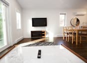 Thumbnail 8 of 24 - a living room with a tv and a table with chairs