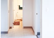 Thumbnail 7 of 13 - Well-lit hallway leading to the bathroom and bedroom in a one-bedroom unit at 1025 Munroe Apartments.