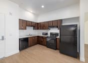 Thumbnail 14 of 15 - A kitchen with black appliances and wooden cabinets.