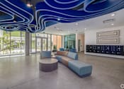 Thumbnail 5 of 15 - A modern interior with a blue ceiling light fixture and a long blue sofa.