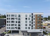 Thumbnail 10 of 24 - A modern multi-story building with a mix of white and wood paneling.