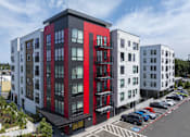 Thumbnail 9 of 24 - A modern multi-story building with a red and black exterior.