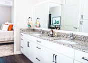 Thumbnail 8 of 68 - En suite bathroom vanity with granite countertops, stain-resistant plank flooring, and a double sink seamlessly connecting to the luxurious master bedroom.
