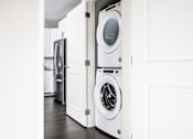 Thumbnail 23 of 68 - Compact stacked washer and dryer nestled in a hallway closet, providing convenient laundry facilities in a stylish apartment.