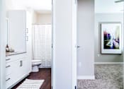 Thumbnail 14 of 68 - Modern apartment bathroom featuring stain-resistant floors and elegant granite countertops. The adjacent spare bedroom boasts plush carpeting and serene nature views.