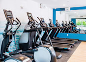 Thumbnail 48 of 68 - Vibrant fitness center within the apartment complex, equipped with modern amenities. The image captures a well-lit space filled with state-of-the-art exercise equipment, including treadmills, elliptical machines, and an array of free weights.