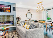 Thumbnail 40 of 68 - Cozy communal lounge in the apartment complex featuring stylish seating arrangements, a modern flat-screen TV, a warm fireplace, and a tabletop shuffleboard for residents to enjoy.
